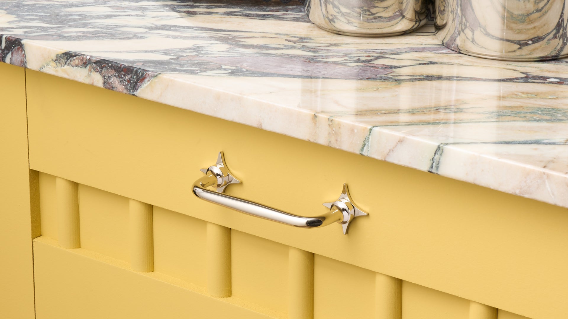 White cupboards with polished nickel handles and star backplates