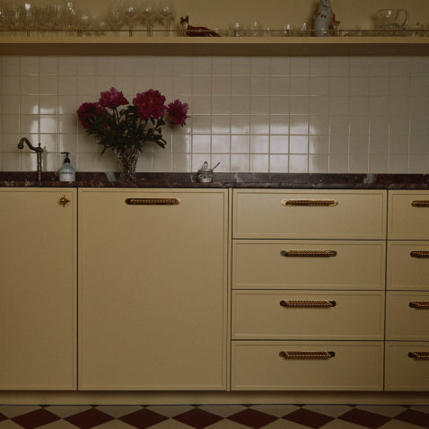 Butter yellow kitchen cabinets with unlacquered brass bobbin handles and backplates